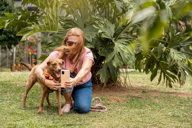 A woman trying to take a selfie with her dog but the wind blows her hair over her face