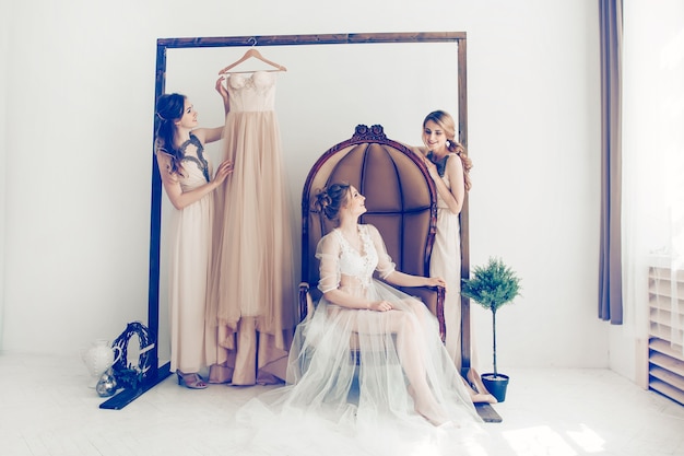 Woman trying on wedding dress with female friends