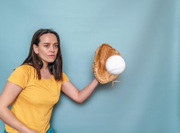 티셔츠를 입은 여성이 야구 글러브에 야구공을 잡는다