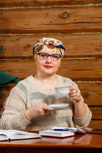 Женщина в тюрбане и очках готовится к семинару дома с чашкой чая