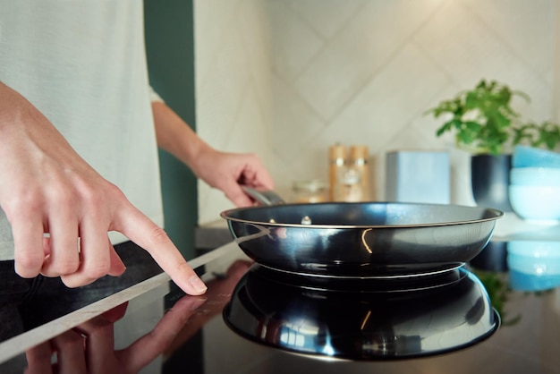 Woman turn on induction hob with frying pan