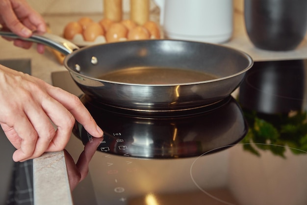 Woman turn on induction hob with frying pan