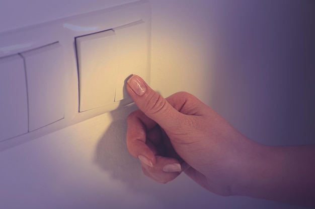 Photo woman turning off light switch indoors closeup energy saving concept