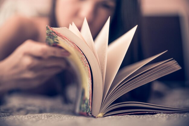 Photo woman turning pages of book on bed