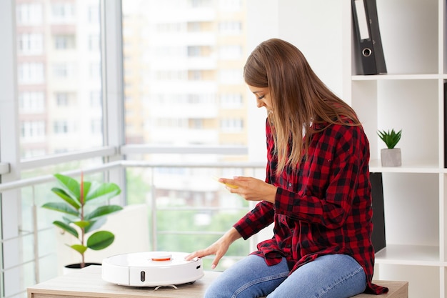 女性がスマートロボット掃除機をオンにします。