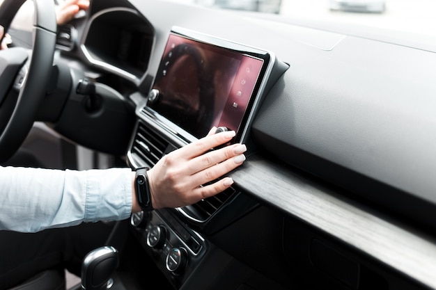 Woman twists the controls on the car radio.