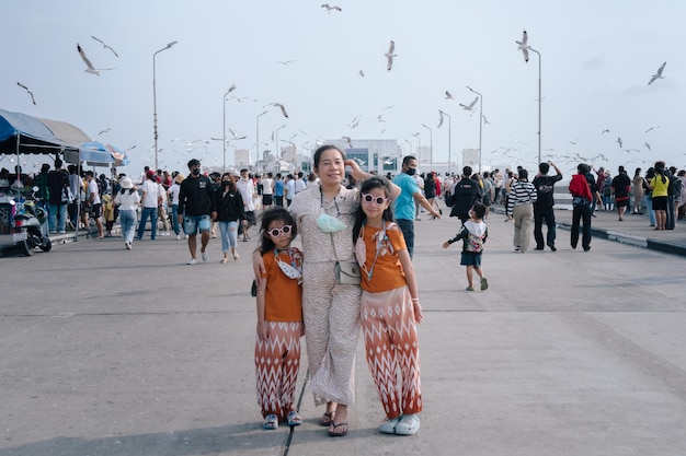 A woman and two girls are standing in front of a crowd of people.