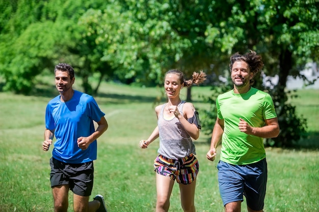 Woman and two young men running in the park