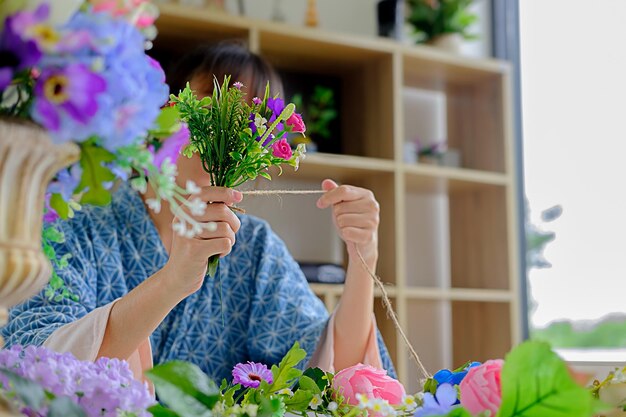 写真 家で花を糸で結ぶ女性