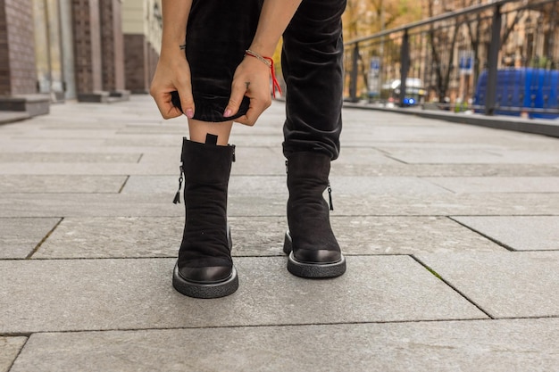 A woman tying her boots on a sidewalk.