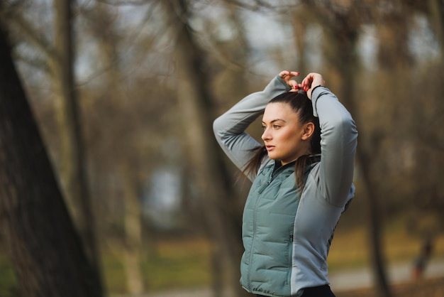 Женщина связывает волосы во время тренировок на открытом воздухе