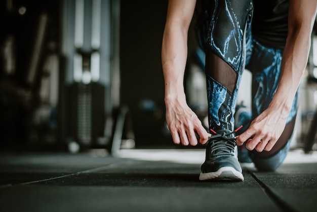 Donna che lega i suoi lacci delle scarpe prima dell'esercizio