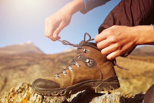 Woman tying hiking boot outdoors on trail in fall