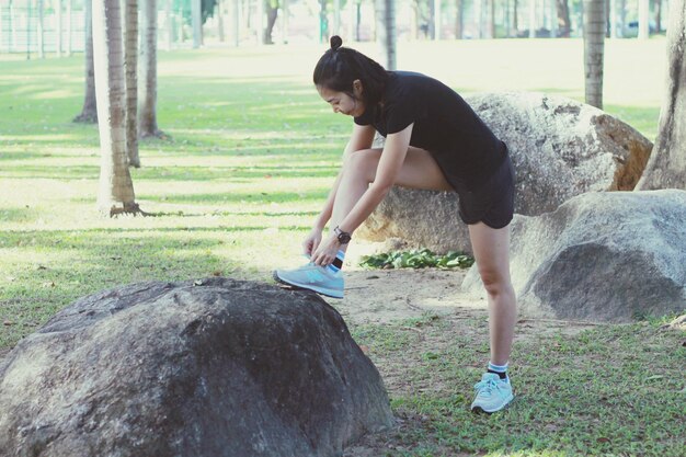 Photo woman tying shoelace on rock