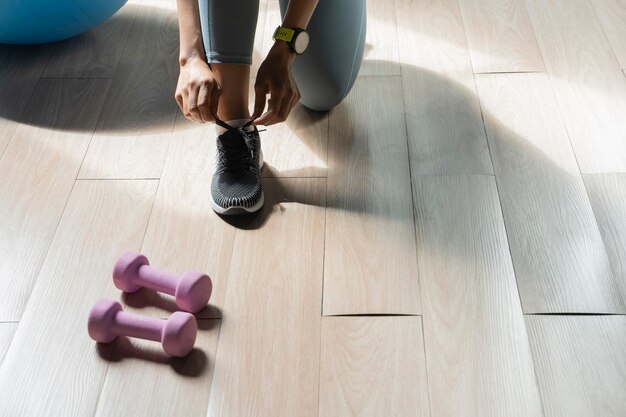 Foto donna che lega i lacci delle scarpe in palestra