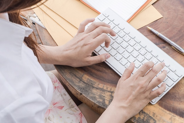 Woman typing on computer keyboard, Low light, selective focus on hand, can be used for e-commerce, business, technology and internet concept