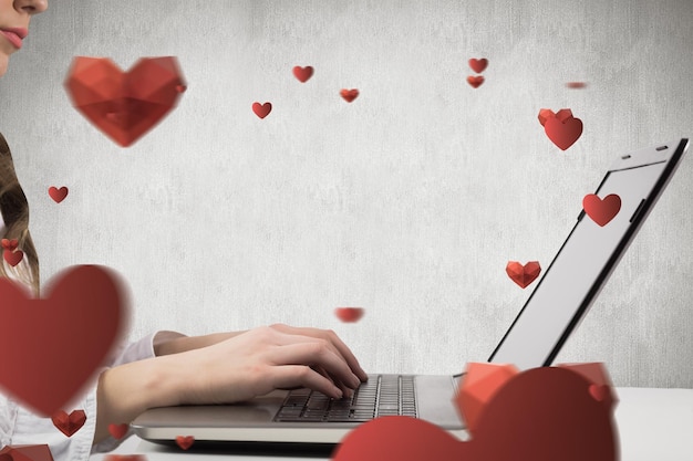 Woman typing on her laptop against white and grey background