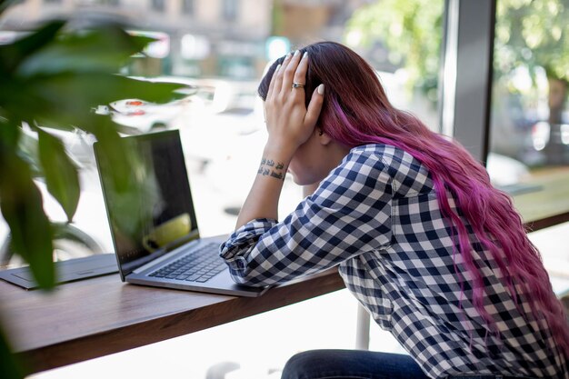 写真 木製のテーブルに座っている空白の画面でノートに入力する女性