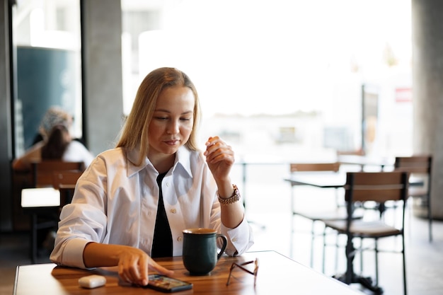 カフェに座りながらスマートフォンでテキストメッセージを入力する女性