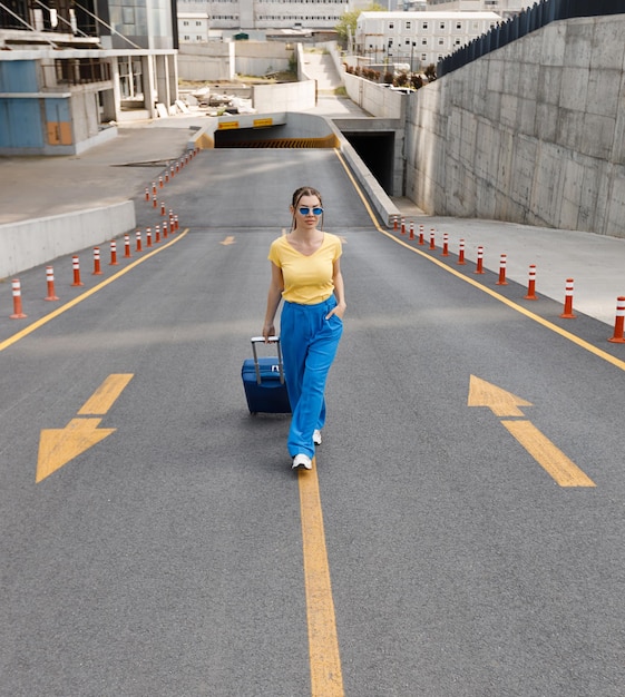 woman in Ukrainian flag colours on the road with suitcase