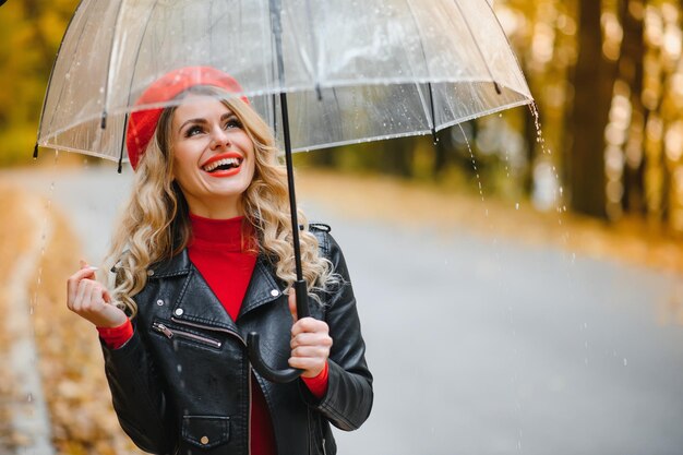 Woman under umbrella walks in the park in autumn