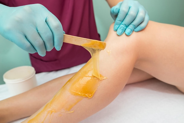 Photo woman undergoing leg hair removal procedure with sugaring paste in salon skin care remove hair with sugar paste