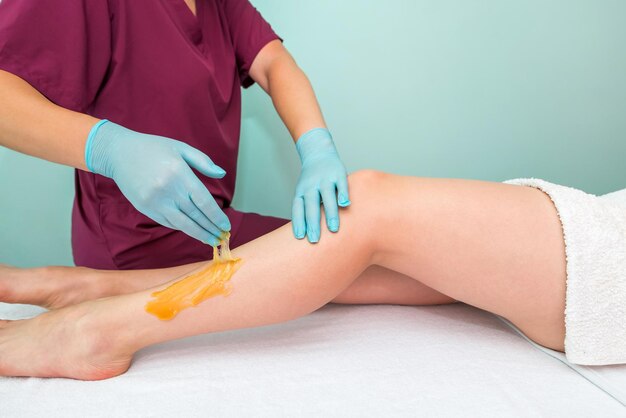 Photo woman undergoing leg hair removal procedure with sugaring paste in salon skin care remove hair with sugar paste
