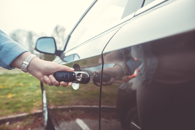 Woman unlocking, opening the car by the vehicle key, safety concept, transportation