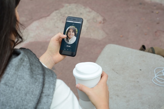 Woman unlocking smartphone with facial recognition technology