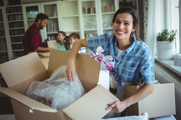 Woman unpackingcarton boxes while family standing in background