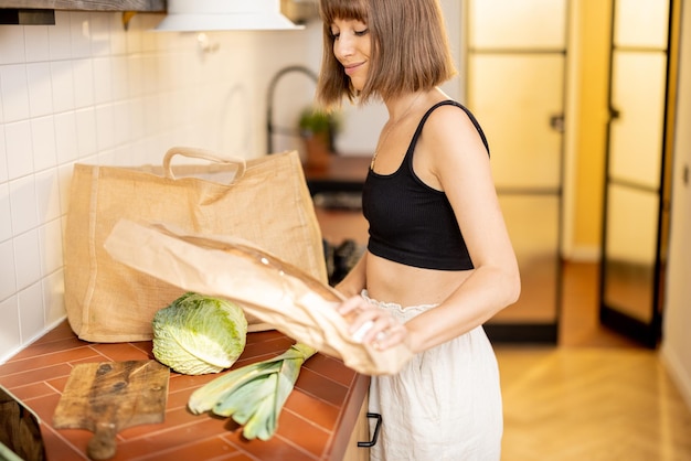 女性は台所のテーブルで買ったばかりの野菜を開梱します