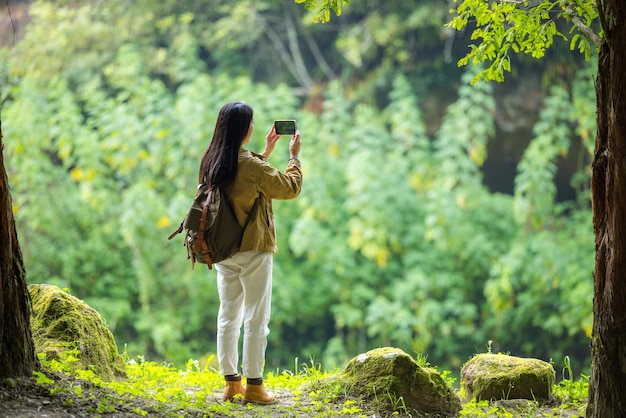 Woman use cellphone to take photo in forest