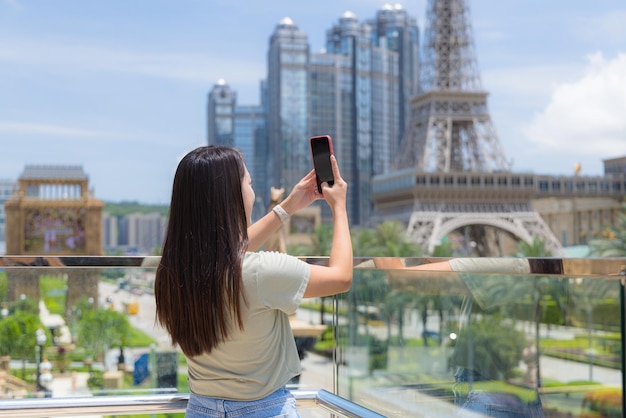 Photo woman use cellphone to take photo of macau city downtown