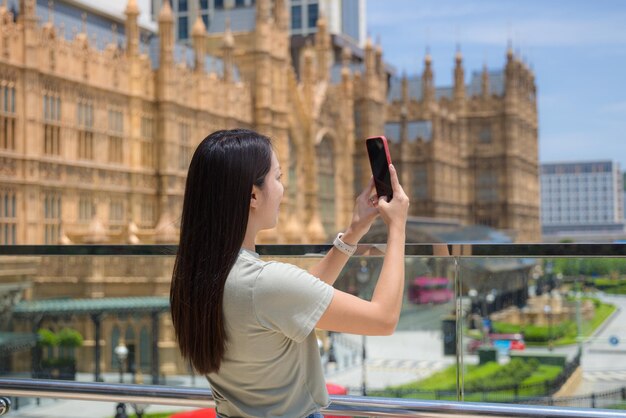 Photo woman use cellphone to take photo of macau city downtown