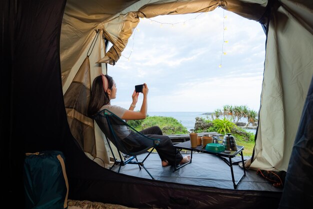 Woman use cellphone to take photo with camping tent