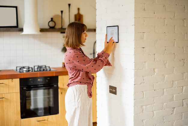 女性はデジタル タブレットを使用してアパートの温度を制御します