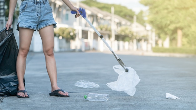 La donna usa l'attrezzatura per la raccolta dei rifiuti mantenendo i rifiuti di plastica nel sacco nero a terra.