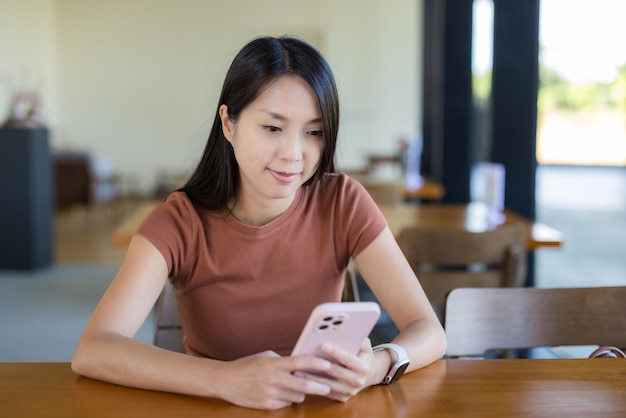 女性がカフェで携帯電話を使っている