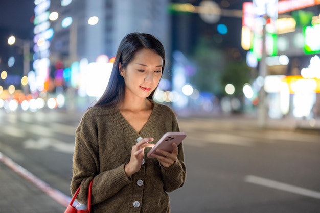 女性が街で夜に携帯電話を使う