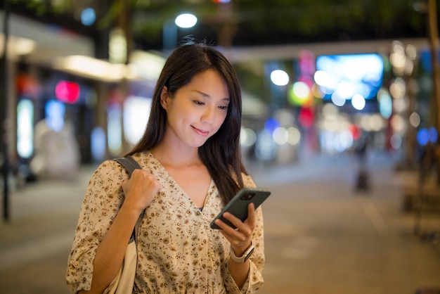 女性が街で夜に携帯電話を使う