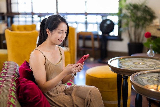 女性がコーヒーショップで携帯電話を使う