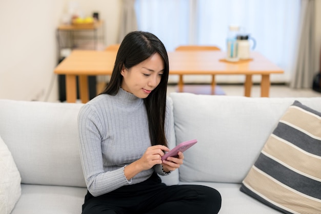 女性が家で携帯電話を使う