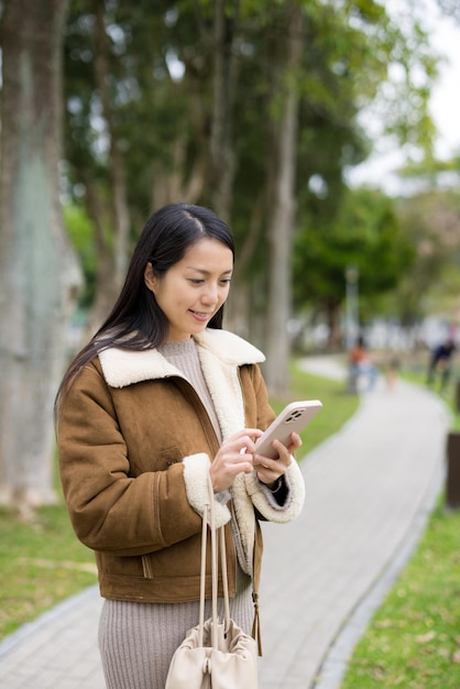 Женщина пользуется мобильным телефоном в парке.