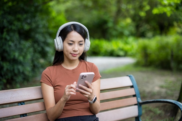 女性が携帯電話を使って公園の中に座っている