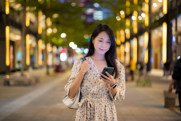 Woman use mobile phone in Taipei city at night