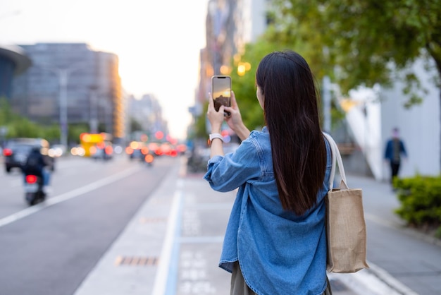 女性が路上で携帯電話を使って写真を撮る