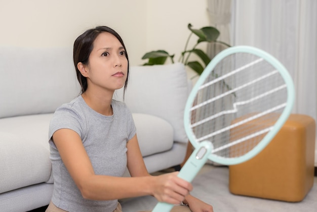 Photo woman use mosquito swatter at home