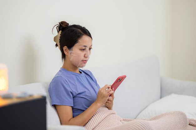 女性は紙のマスクを使用し,家庭で携帯電話を使用します.
