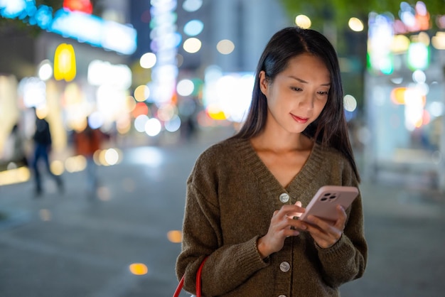 女性が夜に街でスマートフォンを使う