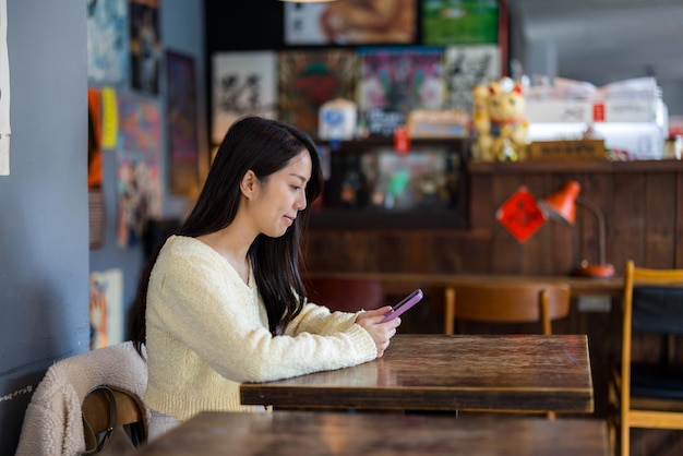 女性がコーヒーショップの内部でスマートフォンを使用